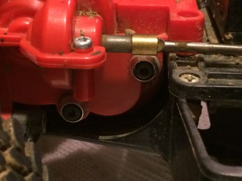 1989 Ford Bronco - A close-up view shows a red plastic component of a vehicle's drivetrain, possibly a gearbox housing, with visible screws and a metal shaft…