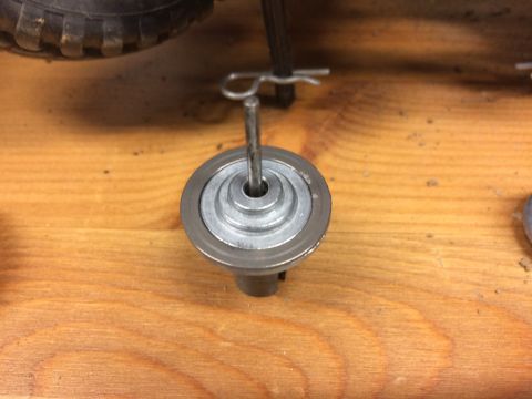 1989 Ford Bronco - A close-up view shows a metal part with concentric rings, possibly a pulley or gear, with a cotter pin inserted through its center. The par…