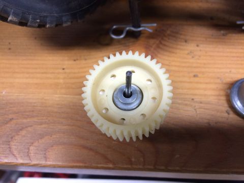 1989 Ford Bronco - A close-up shot of a plastic gear with a metal shaft protruding from its center, resting on a wooden surface. The gear is light-colored and…
