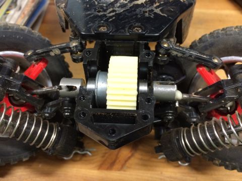 1989 Ford Bronco - Close-up view of the differential and suspension components of a remote-controlled car. The image shows a yellow gear, metal drive shafts,…