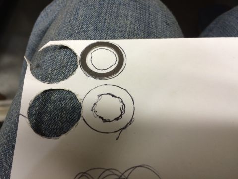 1989 Ford Bronco - A piece of white paper with several circles drawn and cut out, resting on a person's blue denim jeans.