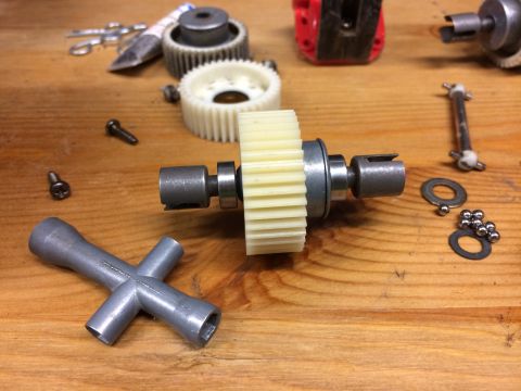 1989 Ford Bronco - A collection of gears, bearings, and tools are laid out on a wooden surface. The parts appear to be from a mechanical assembly, possibly fo…