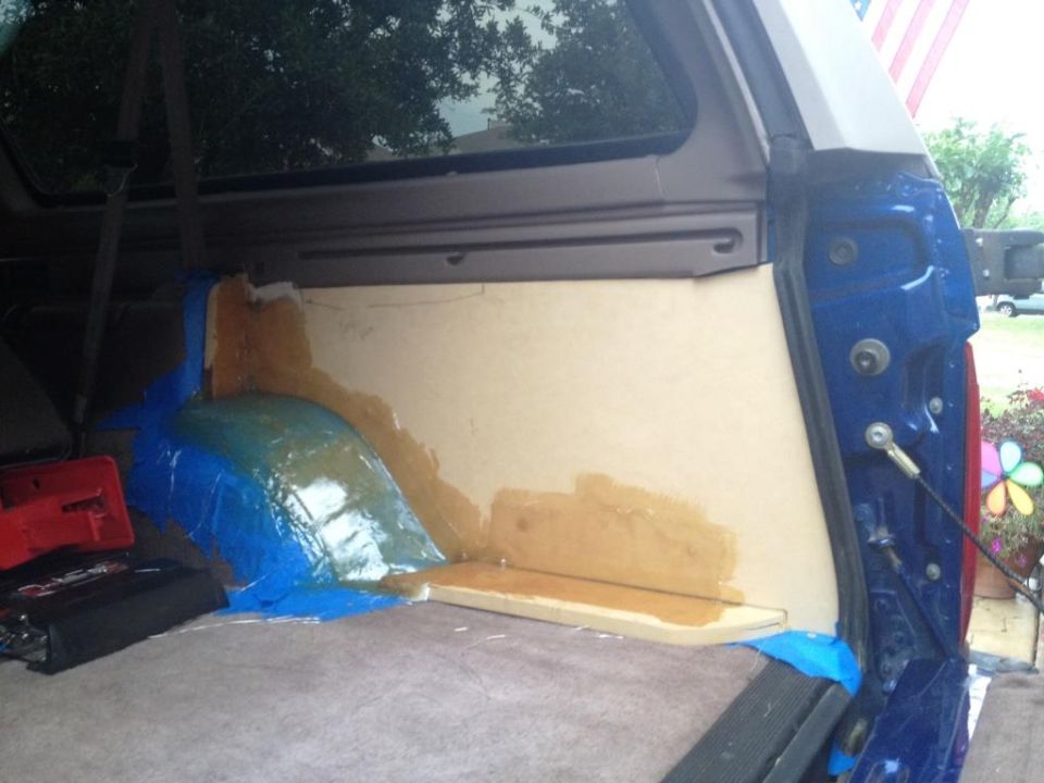 Interior of a blue Ford Bronco showing custom panel installation in cargo area.