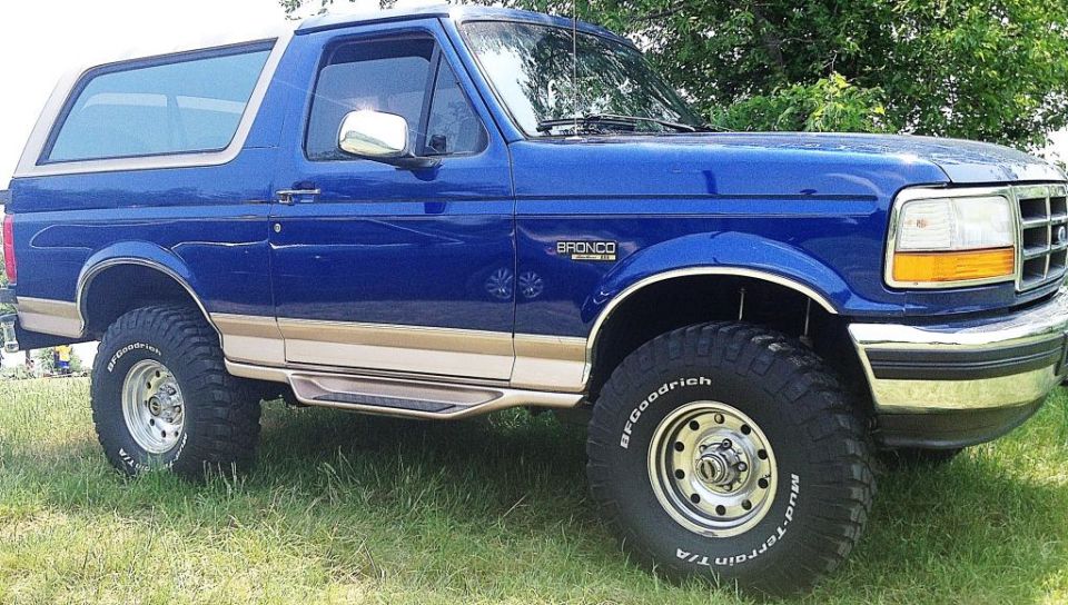 1996 Ford Bronco, blue with tan trim, BFGoodrich tires, parked on grass.