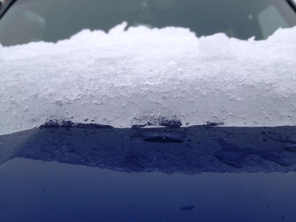Snow and ice on the hood of a dark blue vehicle.