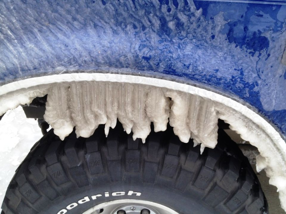 Icicles hanging from the wheel well of a blue vehicle over a BFGoodrich tire.