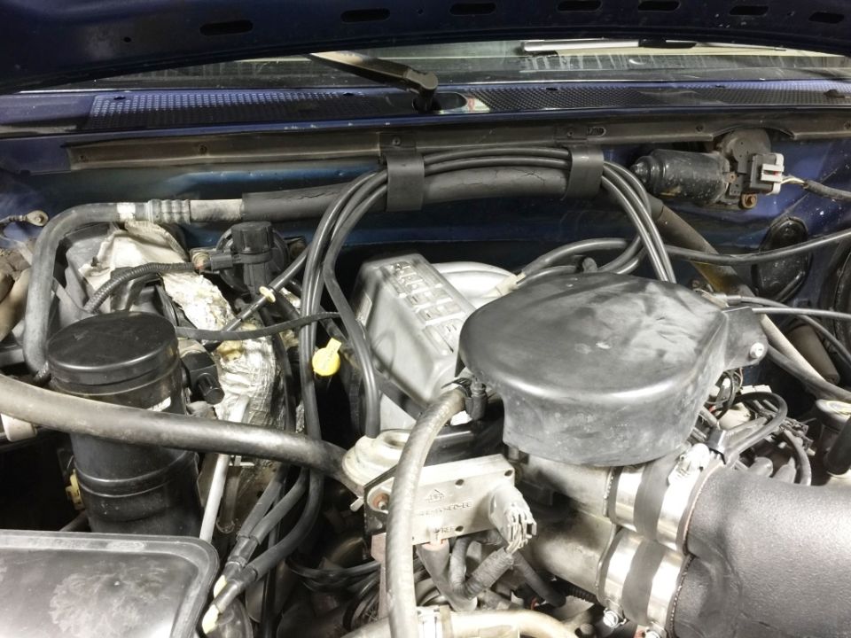 Engine bay of a blue Ford Bronco with black air intake.