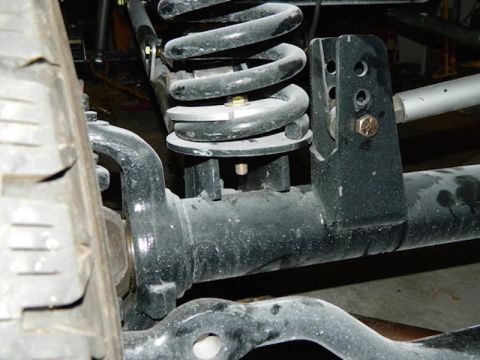 1981 Ford Bronco - A close-up view of the suspension system of a 1981 Ford Bronco, showcasing the coil spring, shock mount, and part of the front axle.