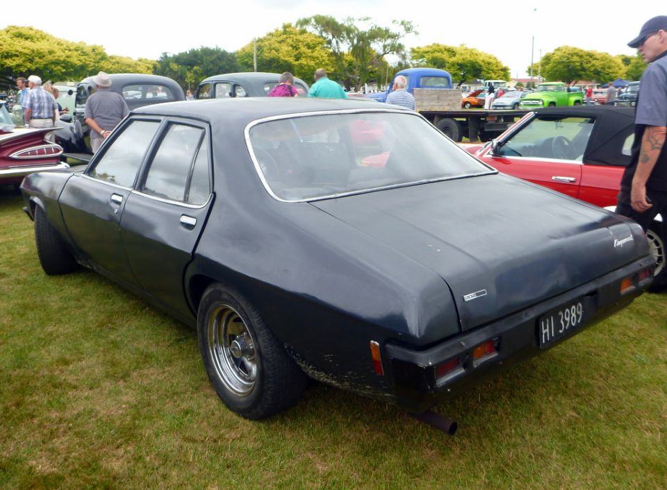 Dark blue sedan, rear view, license plate HI 3989, parked on grass