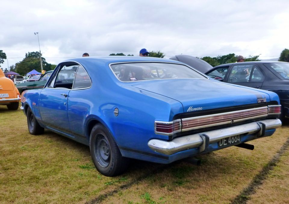 Blue 1969 Holden Monaro GTS coupe, rear driver's side view, parked on grass.