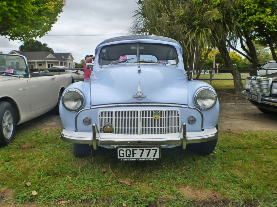 Front view of a light blue classic car with a chrome grille and license plate GQF 777.
