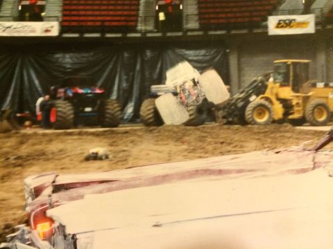 1989 Ford Bronco - Monster truck competition with a loader vehicle and another truck visible in the background.