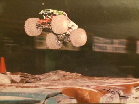 1989 Ford Bronco - Monster truck airborne over a pile of wreckage during a competition.