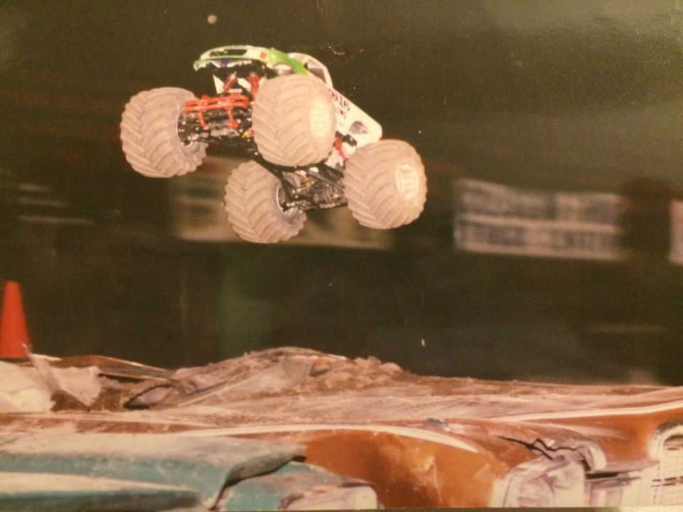 Monster truck mid-air jump over crushed cars