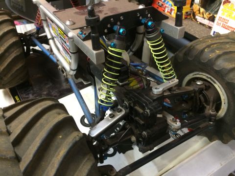 1989 Ford Bronco - A close-up view of the suspension and drivetrain of a remote-controlled monster truck, featuring large, knobby tires and bright yellow shoc…