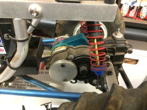 1989 Ford Bronco - Close-up view of the suspension and motor assembly of an RC car, featuring red coilover springs and blue shock bodies.