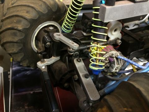 1989 Ford Bronco - Close-up view of the suspension and steering components of a remote-controlled monster truck, showing a large tire, shock absorber with a y…