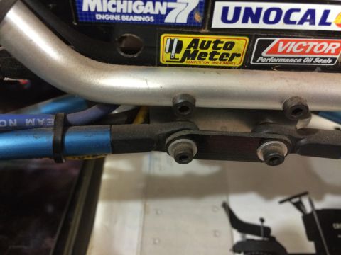 1989 Ford Bronco - Close-up view of a blue hose secured with a black zip tie to a metal component. Visible stickers on a black surface above include 'Auto Met…