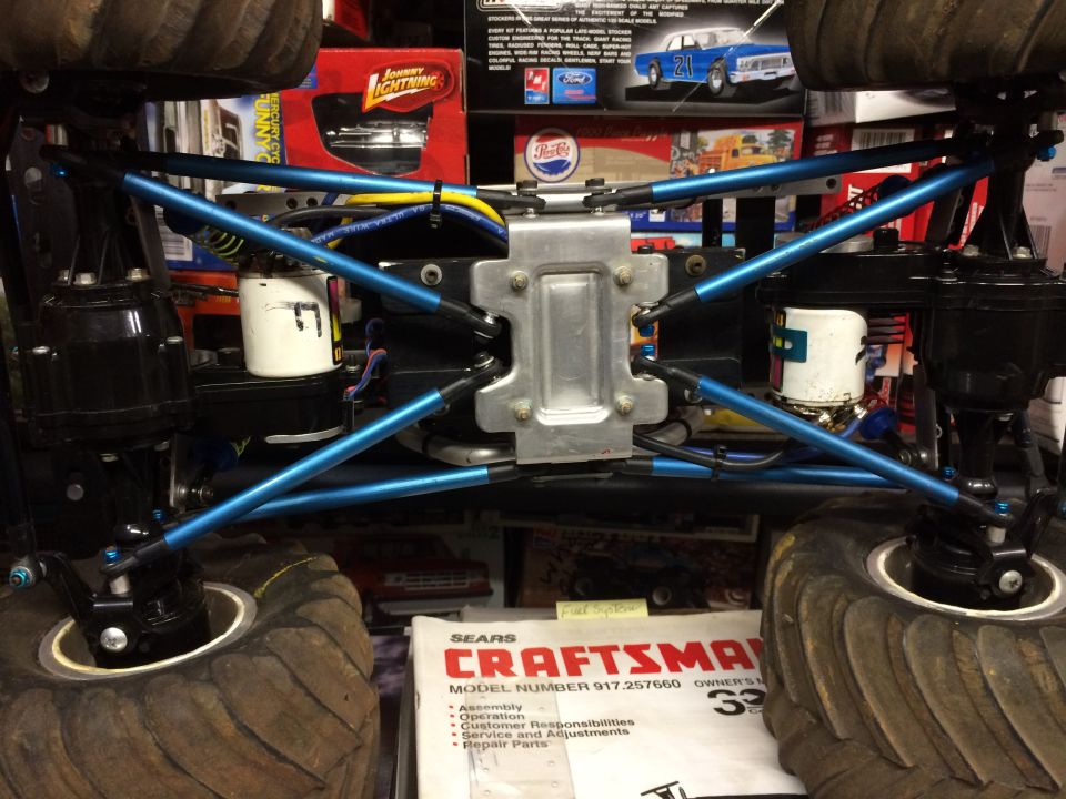 Underside of RC monster truck with blue suspension, large tires, and Craftsman manual.