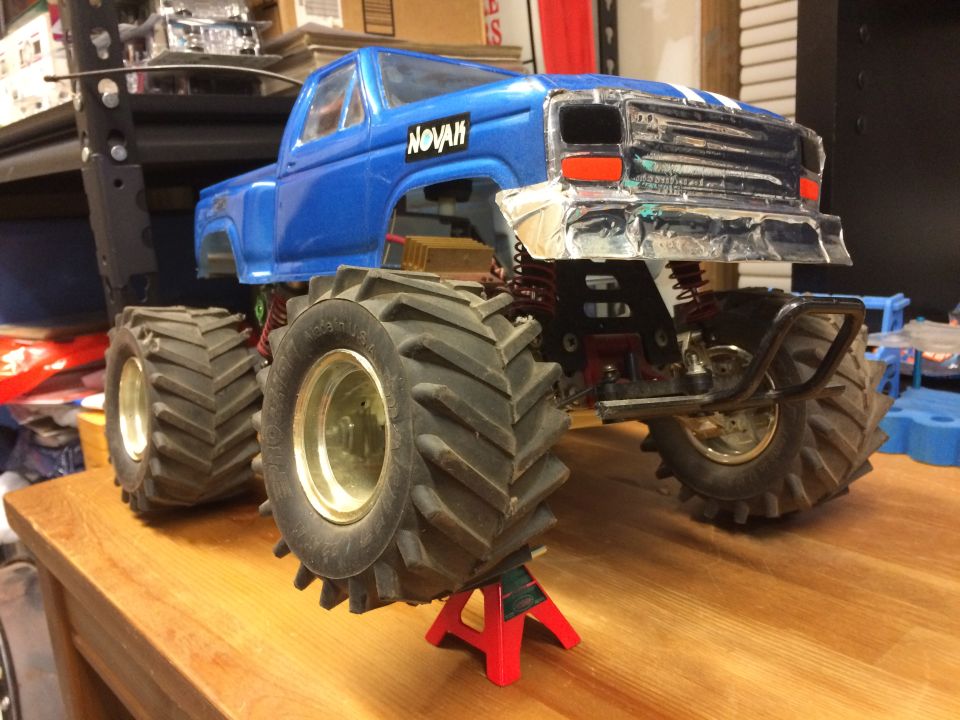 Blue RC monster truck with large tires on jack stands.