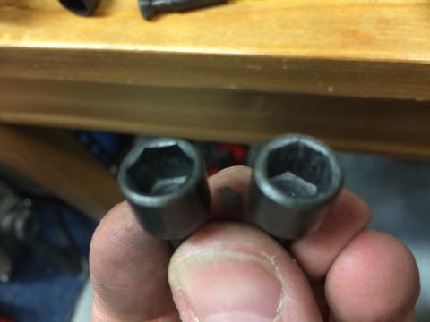 1989 Ford Bronco - A close-up shot shows two hex sockets held in a person's hand. The sockets are dark gray and appear to be made of metal.