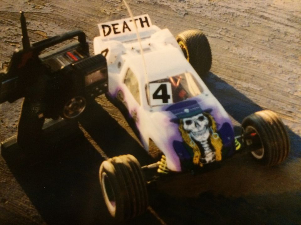Remote-controlled car with skull graphic and "DEATH" sign, next to controller.