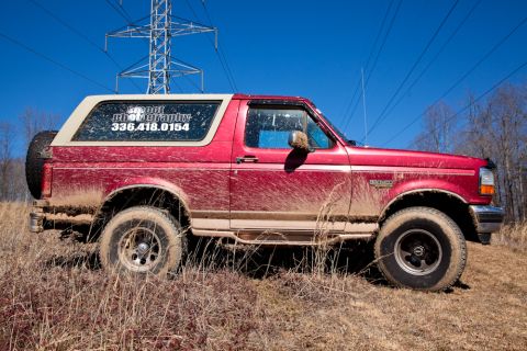 1995 Ford Bronco - This red Ford Bronco is covered in mud, suggesting it has been off-roading.
