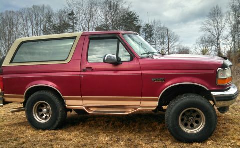 1995 Ford Bronco - Side view of a red 1995 Ford Bronco, lifted with aftermarket wheels and tires.