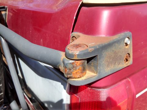 1995 Ford Bronco - Close-up of a rusted trailer hitch mount on the rear of a red vehicle.