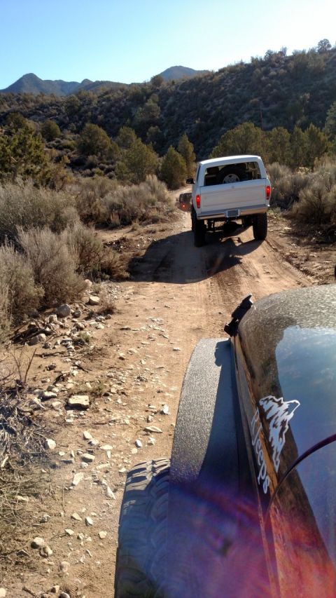1979 Ford Bronco - Two vehicles navigate a dusty, off-road trail through a mountainous, arid landscape.