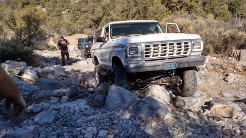 1979 Ford Bronco - White Ford Bronco and a Jeep off-roading on a rocky trail.
