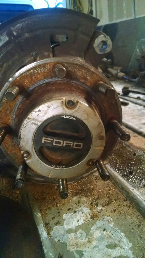 1979 Ford Bronco - Close-up of a rusty Ford hubcap, likely from a truck or SUV, showing wear and tear.