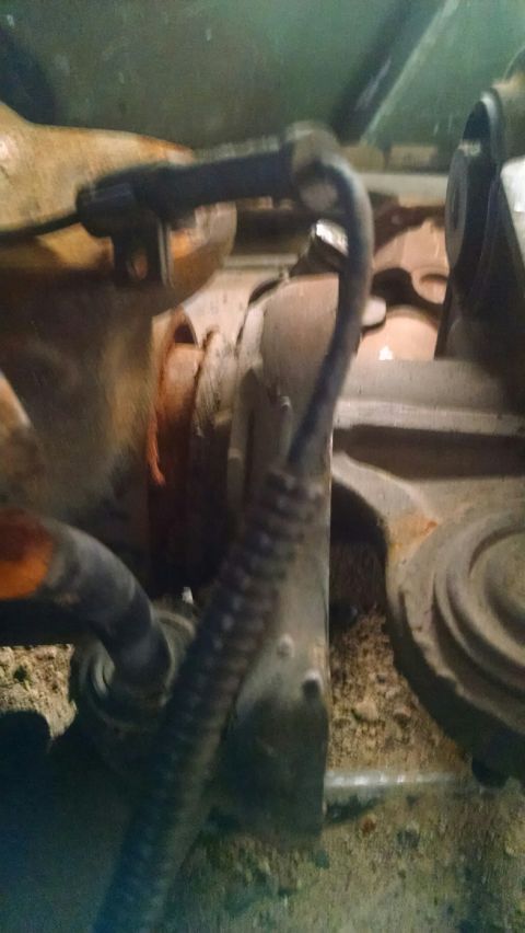 1979 Ford Bronco - Detail shot of rusty suspension components and a black hose, likely from a vehicle's undercarriage.