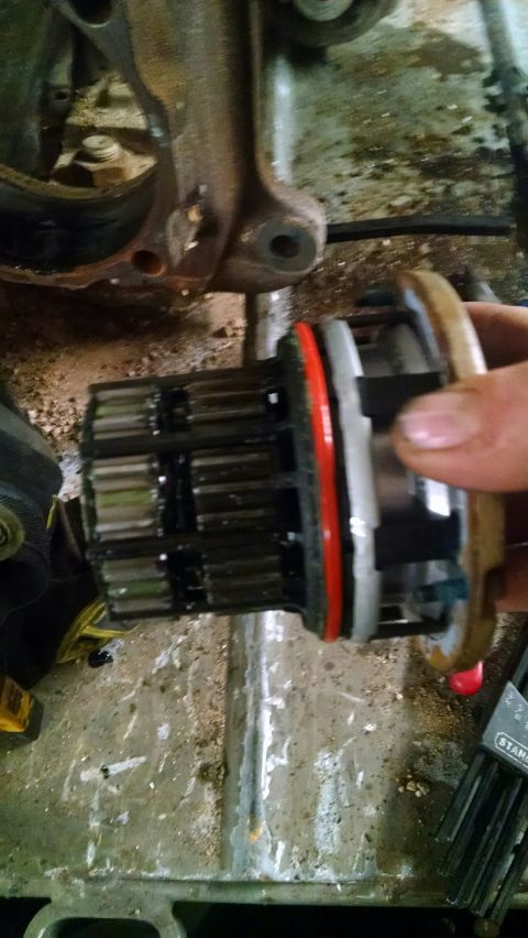 1979 Ford Bronco - Mechanic holding a geared auto part, likely a hub assembly, with a metal bracket in the background.