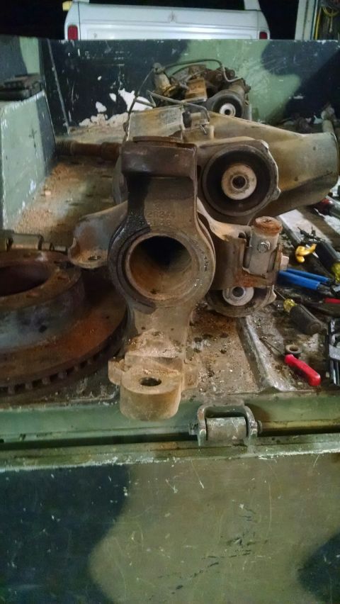 1979 Ford Bronco - A disassembled vehicle axle assembly sits on a surface with various tools scattered around it.