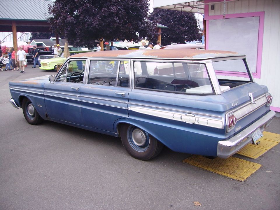 Blue station wagon with chrome trim and rusty roof, seen from the rear
