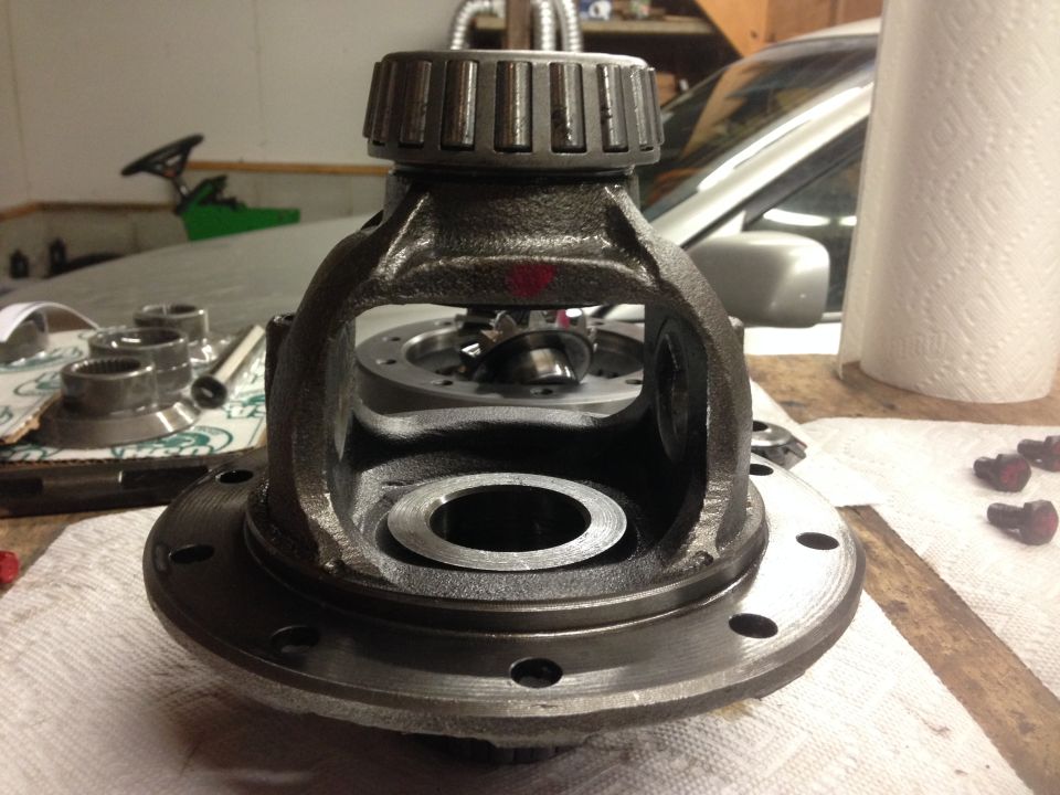 Differential carrier with a bearing race on top, sitting on a workbench with gears visible inside