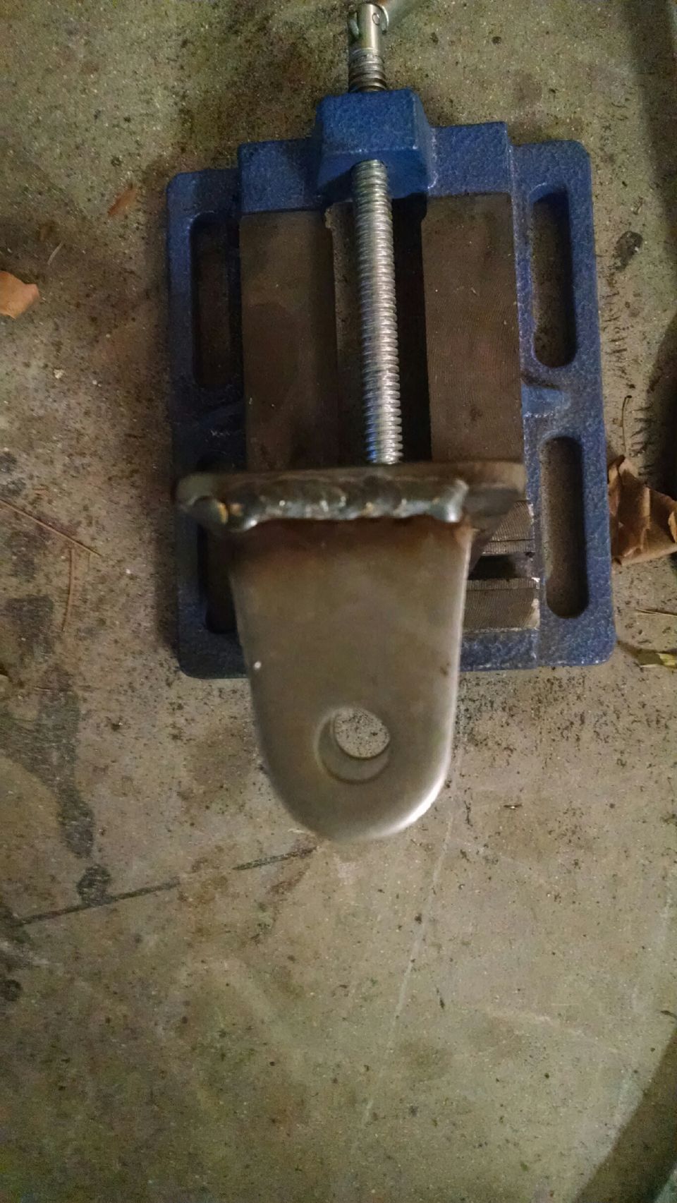 Metal part with a hole, clamped in a blue vise