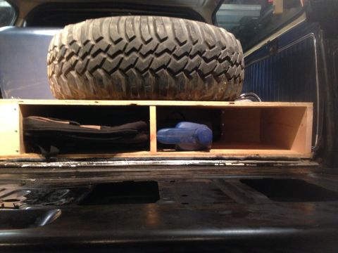 1979 Ford Bronco - Spare tire and storage box with tools visible in the cargo area of a vehicle.