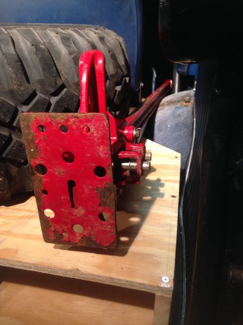 1979 Ford Bronco - A red hi-lift jack is mounted next to a spare tire, likely in the storage area of a vehicle.