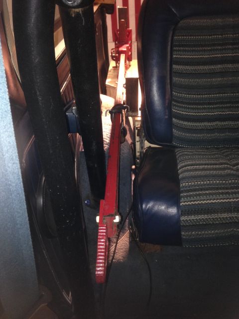 1979 Ford Bronco - A red jack is visible in the storage compartment of a vehicle, next to a blue and striped seat.