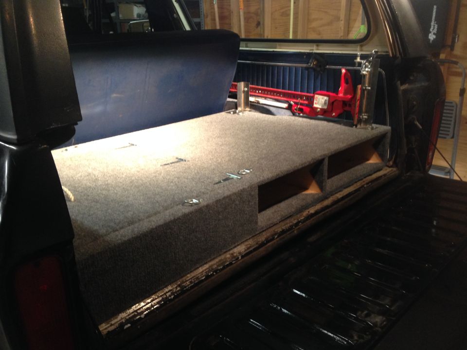 Interior view of a 1979 Ford Bronco with a custom carpeted storage box installed in the rear cargo area