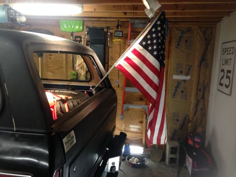1979 Ford Bronco - Rear view of a 1979 Ford Bronco in a garage, adorned with an American flag and a "600 Days Topless" sticker.
