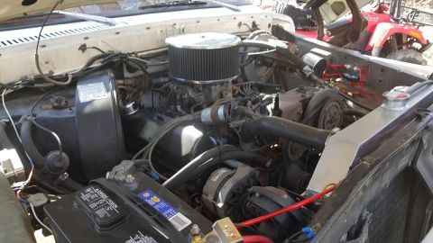 1978 Ford Bronco - The engine bay of a vehicle, a V8 engine, air filter, and radiator. An ATV is visible in the background.