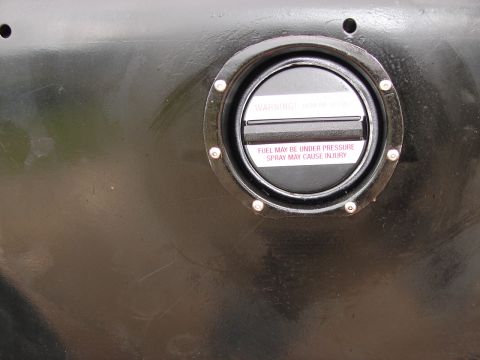 1964 Volkswagen Beetle - A close-up of a black fuel cap on a vehicle's body, showing warning labels.