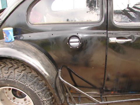 1964 Volkswagen Beetle - Side view of a black Volkswagen Beetle, modified with off-road tires and external roll cage elements.