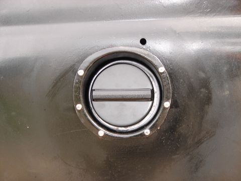 1964 Volkswagen Beetle - Close-up view of a black fuel filler cap on a vehicle's body panel.