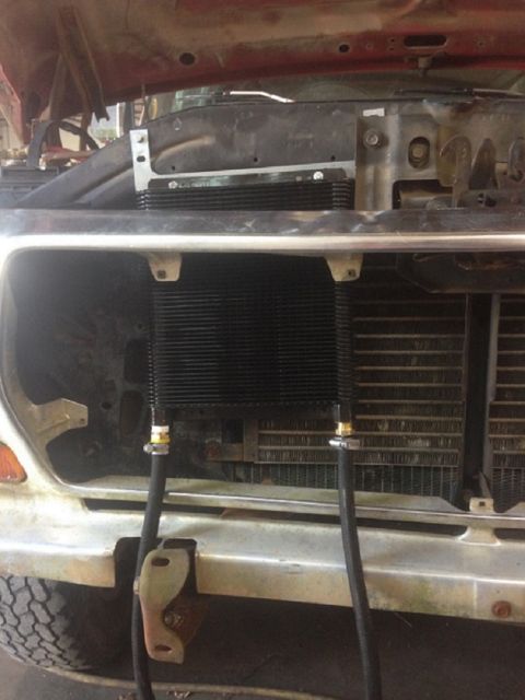1978 Ford Bronco - Installing an aftermarket transmission cooler in front of the vehicle's radiator.
