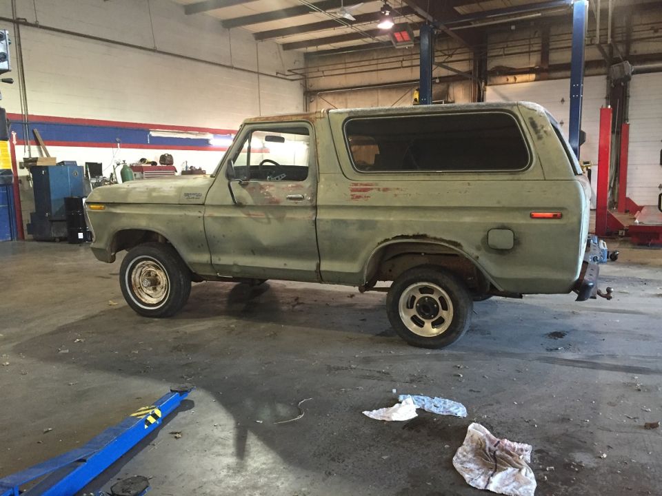 1978 Ford Bronco in a garage, side view. It has some rust and is in need of repair
