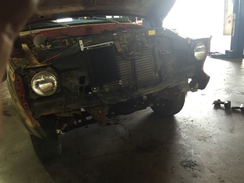 1978 Ford Bronco - The front end of a 1978 Ford Bronco is visible, with the hood up and parts removed for repair.